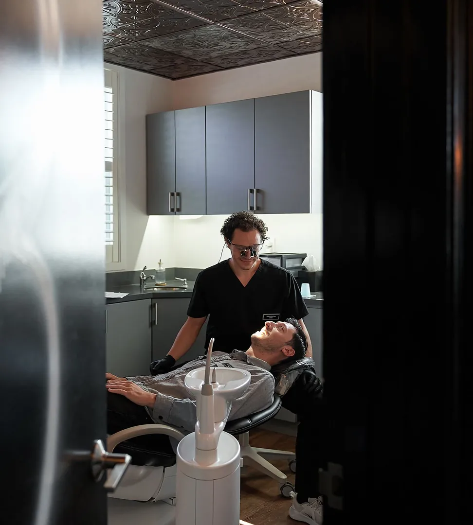 Dr. Nelson DeLima examining a patient, seen through the doorway at Red Bank Smiles in Red Bank, NJ