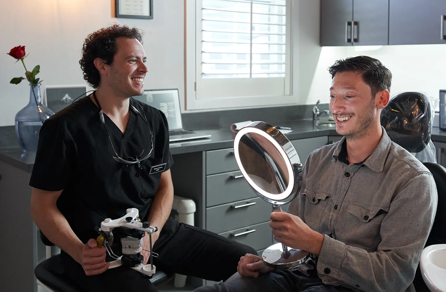 Dr. Nelson DeLima showing a patient his smile in a mirror at Red Bank Smiles in Red Bank, NJ